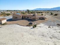 Aerial view of a unique, single-story home with desert landscaping and distant mountain views at 3281 Mark Rd, Pahrump, NV 89060
