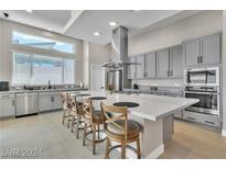 This kitchen offers grey cabinets, stainless appliances, an island with seating, and lots of natural light at 10301 Fairview Ridge Ct, Las Vegas, NV 89166