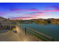 Scenic lakeside view of a building with ornate details, balconies, and a vibrant sunset in the background at 36 Lakefront Dr, Henderson, NV 89011