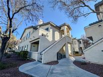 Two-story stucco building with walkway, landscaping, and trees at 3103 Key Largo Dr # 103, Las Vegas, NV 89120