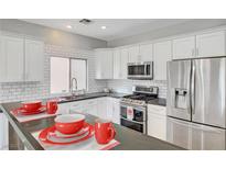 Modern kitchen with stainless steel appliances, white cabinets, and a tiled backsplash at 5919 Pavilion Lakes Ave, Las Vegas, NV 89122