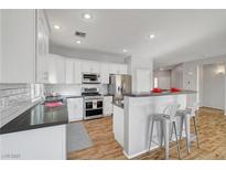 A modern kitchen featuring white cabinets, stainless steel appliances, and a breakfast bar with seating at 5919 Pavilion Lakes Ave, Las Vegas, NV 89122