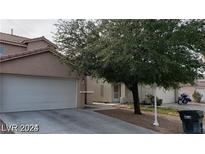 Beige house with a two-car garage and mature tree in front at 5987 Stone Hollow Ave, Las Vegas, NV 89156