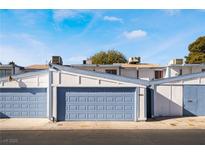 Front view of a townhouse with a two-car garage and blue doors at 4071 Village Sq, Las Vegas, NV 89121