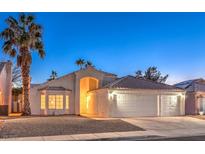 Two-car garage, attractive landscaping, and warm lighting enhance the curb appeal of this charming home at 1183 Winnipeg Ct, Henderson, NV 89002