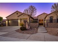 Single-story home with two-car garage, landscaped yard, and decorative iron fencing at 2378 Sandstone Cliffs Dr, Henderson, NV 89044