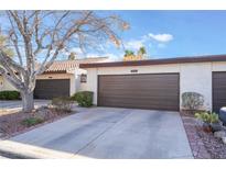 Front view of a tan house with a brown garage door and landscaping at 2847 San Martin Ct, Las Vegas, NV 89121