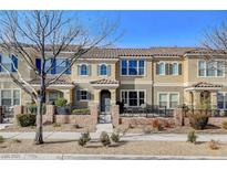 Tan two-story townhome with gray door, and a small front patio at 2077 Via Firenze, Henderson, NV 89044