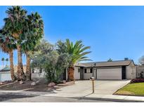 Single-story home with attached two-car garage, landscaping, and palm trees at 4457 Dennis Way, Las Vegas, NV 89121