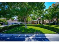 Beautiful two-story house with a lush green lawn and mature trees at 56 Sawgrass Ct, Las Vegas, NV 89113