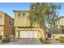 Two-story house with tan exterior, two-car garage, and landscaping at 8031 Tank Loop St, Las Vegas, NV 89166