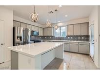 Modern kitchen with stainless steel appliances, large island, pendant lighting, and decorative tile backsplash at 8031 Tank Loop St, Las Vegas, NV 89166