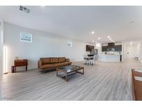 Spacious open-concept living area with modern gray flooring, a brown leather sofa, and a coffee table at 3540 Valley Lily St, North Las Vegas, NV 89032