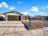 Single-story home with a dark brown garage door and well-maintained front yard at 4917 E Washington Ave, Las Vegas, NV 89110