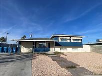 Ranch style home with blue exterior, gravel landscaping, and a paved driveway at 6124 Jones Cir, Las Vegas, NV 89107