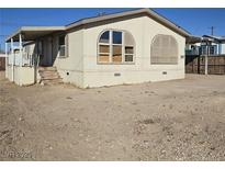 Tan mobile home with covered porch and large windows, situated on a lot with dirt landscaping at 6214 Mount Rainier Ave, Las Vegas, NV 89156