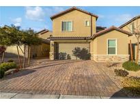 Tan two-story house with a two-car garage and a brick paved driveway at 4372 Latitude Valley Ct, North Las Vegas, NV 89084