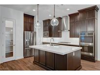 Modern kitchen featuring stainless steel appliances, dark cabinets, an island, and decorative pendant lighting at 395 Nine Mile Creek Dr, Las Vegas, NV 89138