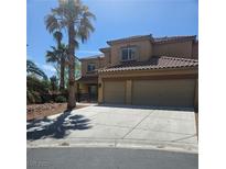 Two story tan home with a large two car garage and beautiful desert landscaping at 5805 Cabo San Lucas Ave, Las Vegas, NV 89131