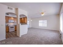 Bright living room with new carpet, a ceiling fan, and views into the kitchen at 6160 Rumrill St # 122, Las Vegas, NV 89113