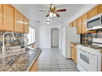 Bright kitchen features granite countertops, wood cabinets, and tile flooring at 10082 Swimming Hole St, Las Vegas, NV 89183