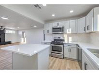 Modern kitchen featuring white shaker cabinets, stainless steel appliances, and a large island at 133 Dogwood St, Henderson, NV 89015