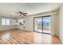 Bright living room featuring wood floors, ceiling fan, and a sliding glass door to the outdoor balcony at 1963 Scimitar Dr # 0, Henderson, NV 89014