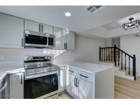 Modern kitchen with gray cabinets, stainless steel appliances, and a breakfast bar at 3367 Vema Dr, Las Vegas, NV 89121