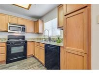 Modern kitchen with granite countertops, black appliances, and light wood cabinets at 833 Aspen Peak Loop # 2524, Henderson, NV 89011