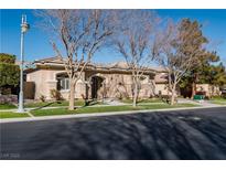 Single-story home with beige exterior, landscaping, and a large front yard at 9316 Provence Garden Ln, Las Vegas, NV 89145