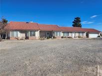 Single-story home with red tile roof and spacious gravel driveway at 2651 Homestead Rd, Pahrump, NV 89048