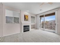 Bright living room featuring a fireplace, plush carpet, and a sliding glass door to a private balcony at 805 Dana Hills Ct # 104, Las Vegas, NV 89134