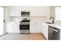 Modern kitchen with white cabinets, stainless steel appliances, and quartz countertops at 886 Park Walk Ave, Las Vegas, NV 89123