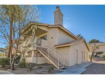 Exterior view of a two-story condo with stairs leading to the entrance and a satellite dish at 1301 Pinto Rock Dr # 201, Las Vegas, NV 89128