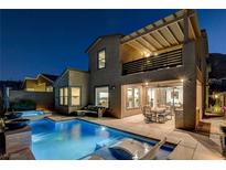 Stunning nighttime view of a home with a sparkling pool, patio furniture, and pergola at 1968 Regal Bluff Dr, Henderson, NV 89052
