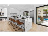 Modern kitchen features marble countertops, stainless steel appliances, and an island with seating at 5637 San Florentine Ave, Las Vegas, NV 89141