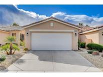 Beige home featuring a two-car garage, rock landscaping and mature trees at 5201 Progresso St, Las Vegas, NV 89135