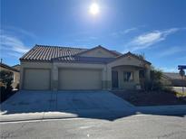 Tan house with three-car garage and desert landscaping at 1105 Bobby Pollard Ave, North Las Vegas, NV 89086