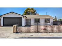 Single story home with dark brown garage door and black metal fence at 4111 E Saint Louis Ave, Las Vegas, NV 89104