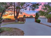 Inviting single-story home with a spacious driveway and lush landscaping at sunset at 5261 S Sandhill Rd, Las Vegas, NV 89120