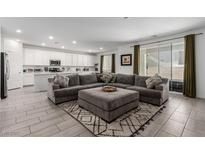 Open living area with gray sectional sofa, ottoman, and large TV at 2883 Gunnery Forge St, Las Vegas, NV 89156