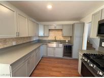 Modern kitchen featuring gray cabinets, stainless steel sink, and wood flooring at 5337 Hacienda Cir, Las Vegas, NV 89120
