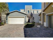 Two-story house with gray siding, a white garage door, and a paved driveway at 7174 Steubling Glen St, North Las Vegas, NV 89084