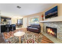 Inviting living room featuring a stone fireplace, TV, and open layout to the kitchen and dining areas at 1321 Cinder Rock Dr # 202, Las Vegas, NV 89128