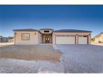 Charming single-story home featuring a three-car garage, desert landscaping, and a welcoming double door entry at 2140 Upland Ave, Pahrump, NV 89048