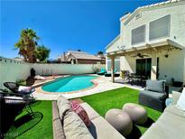 Inviting backyard oasis with a sparkling pool, lush grass, and patio furniture at 8233 Hydra Ln, Las Vegas, NV 89128