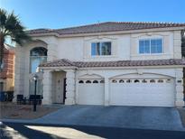 Two-story home featuring a red tile roof, stucco exterior, arched windows, and a two car garage at 6509 Alpine Winter Ct, Las Vegas, NV 89149