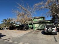 Two-story house with a green exterior, driveway, and mature trees at 2180 Palora Ave, Las Vegas, NV 89169