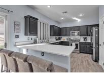 Modern kitchen featuring dark cabinetry, quartz countertops, and stainless steel appliances at 5313 Dawn Break Canyon St, North Las Vegas, NV 89031