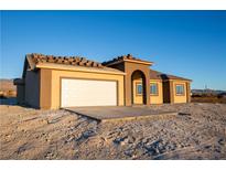 Tan stucco home with a white garage door and arched entryway at 5821 Genoa Ave, Pahrump, NV 89060